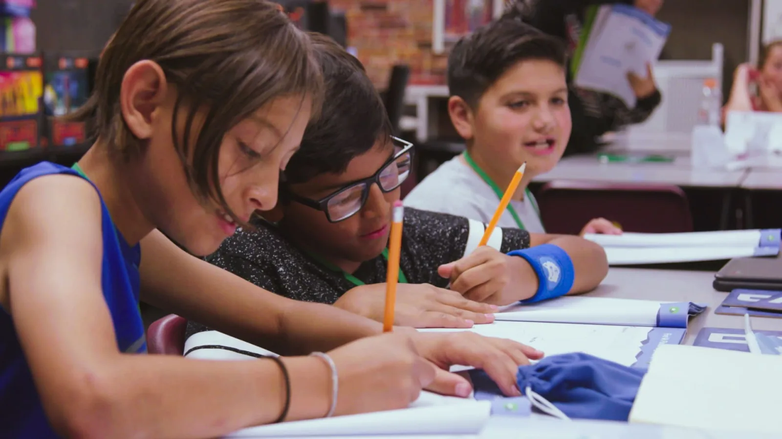 Students writing in workbooks together at a shared desk